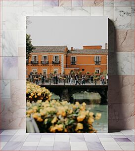 Πίνακας, People Walking on a Bridge in Front of an Orange Building Άνθρωποι που περπατούν σε μια γέφυρα μπροστά από ένα πορτοκαλί κτήριο