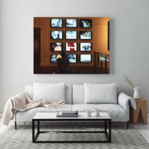 Πίνακας, ένα άτομο που κάθεται σε ένα παγκάκι μπροστά από έναν τοίχο τηλεοράσεων