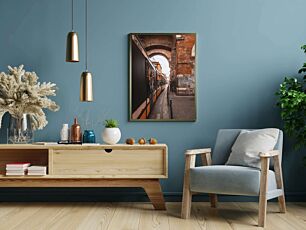 Πίνακας, ένα τρένο που ταξιδεύει κάτω από μια γέφυρα δίπλα σε ένα ψηλό κτίριο από τούβλα
