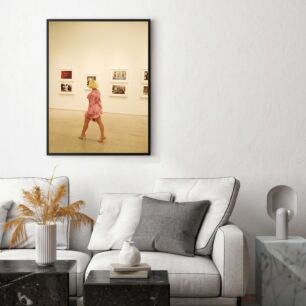 Πίνακας, μια γυναίκα που περπατά μπροστά από έναν τοίχο με φωτογραφίες πάνω του