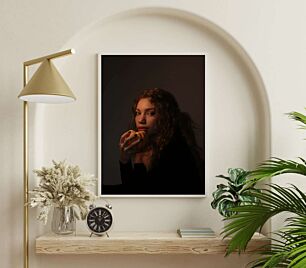 Πίνακας, μια γυναίκα με σγουρά μαλλιά που τρώει ένα ντόνατ