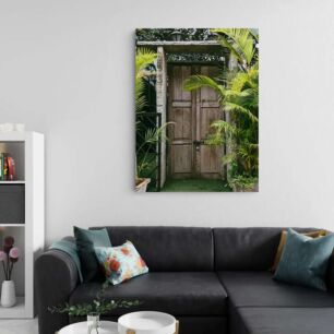 Πίνακας, μια ξύλινη πόρτα που περιβάλλεται από φοίνικες και φυτά σε γλάστρες